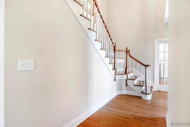 staircase with a high ceiling and wood-type flooring