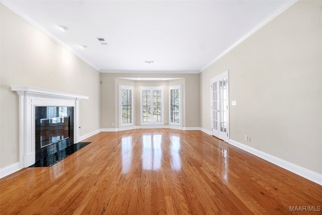 unfurnished living room featuring a high end fireplace, crown molding, and hardwood / wood-style floors