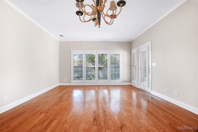 spare room featuring a notable chandelier, light hardwood / wood-style floors, and crown molding