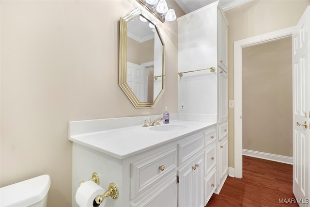 bathroom with crown molding, toilet, vanity, and hardwood / wood-style flooring