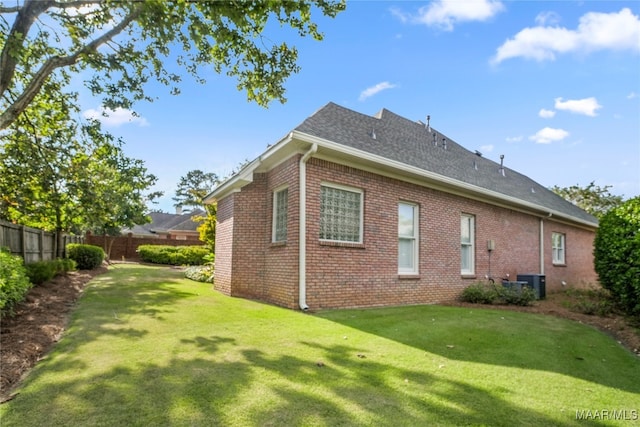 view of side of home with central AC unit and a lawn