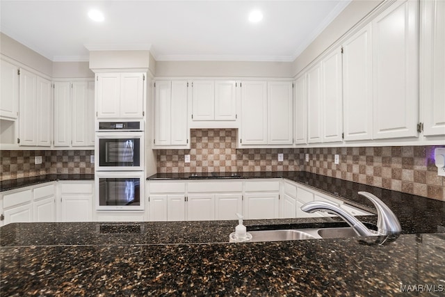 kitchen with tasteful backsplash, multiple ovens, and white cabinetry