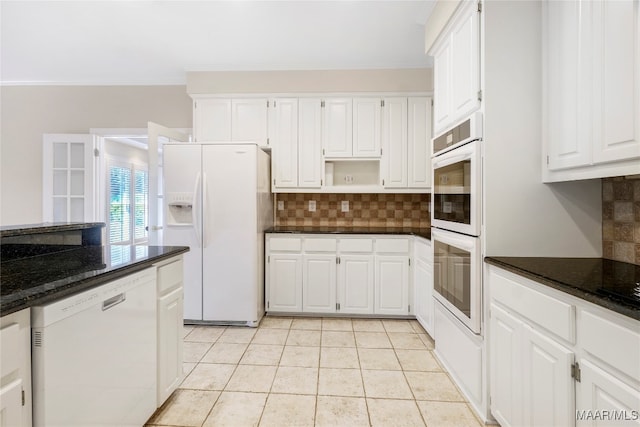 kitchen featuring backsplash, white appliances, dark stone counters, and white cabinets