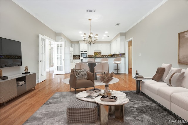 living room featuring ornamental molding, an inviting chandelier, and hardwood / wood-style floors