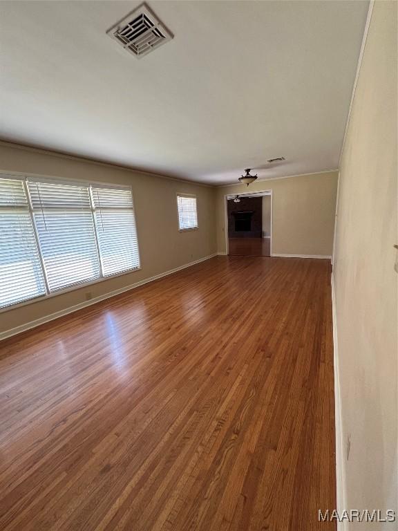 unfurnished living room with baseboards, wood finished floors, and visible vents