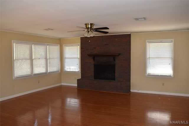 unfurnished living room featuring a fireplace, crown molding, dark hardwood / wood-style flooring, and ceiling fan