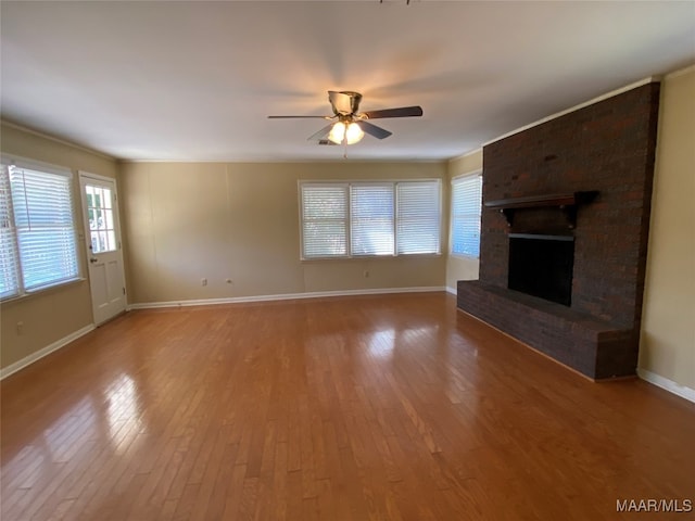 unfurnished living room with wood-type flooring, ceiling fan, and a brick fireplace