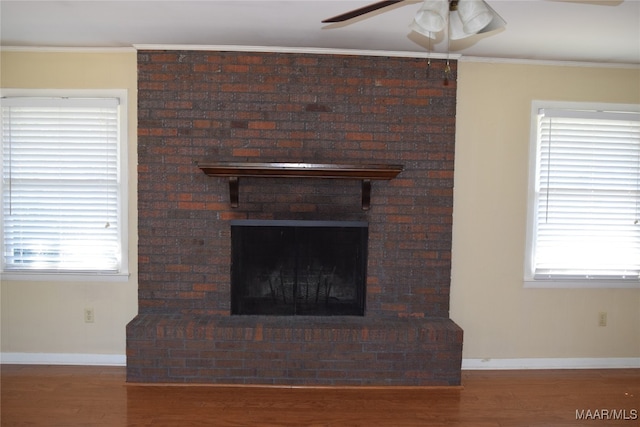 interior details featuring wood-type flooring, ceiling fan, ornamental molding, and a brick fireplace