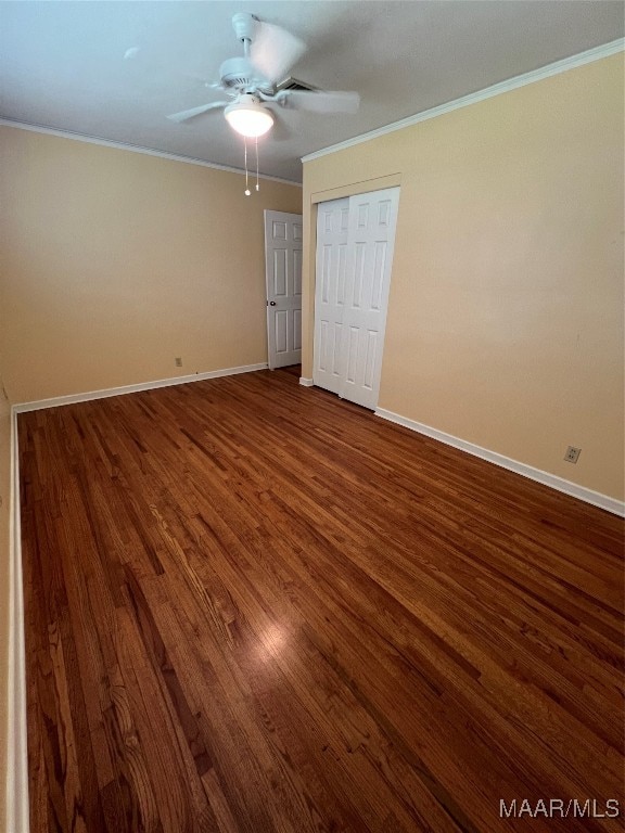 unfurnished bedroom with ornamental molding, ceiling fan, dark hardwood / wood-style floors, and a closet