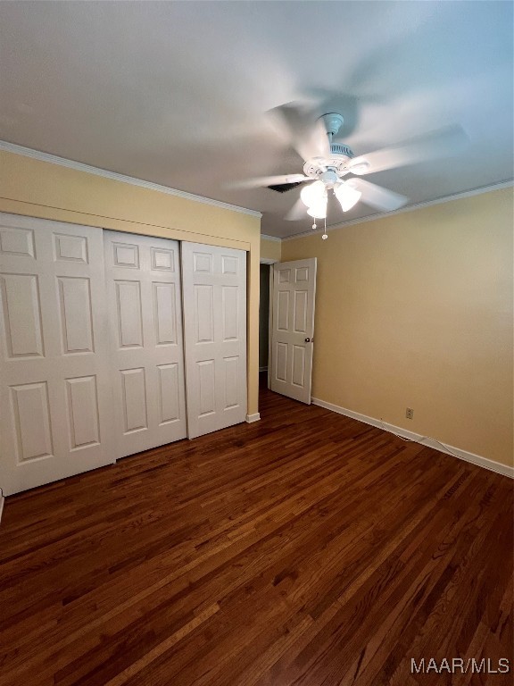 unfurnished bedroom featuring a closet, ceiling fan, dark hardwood / wood-style flooring, and ornamental molding