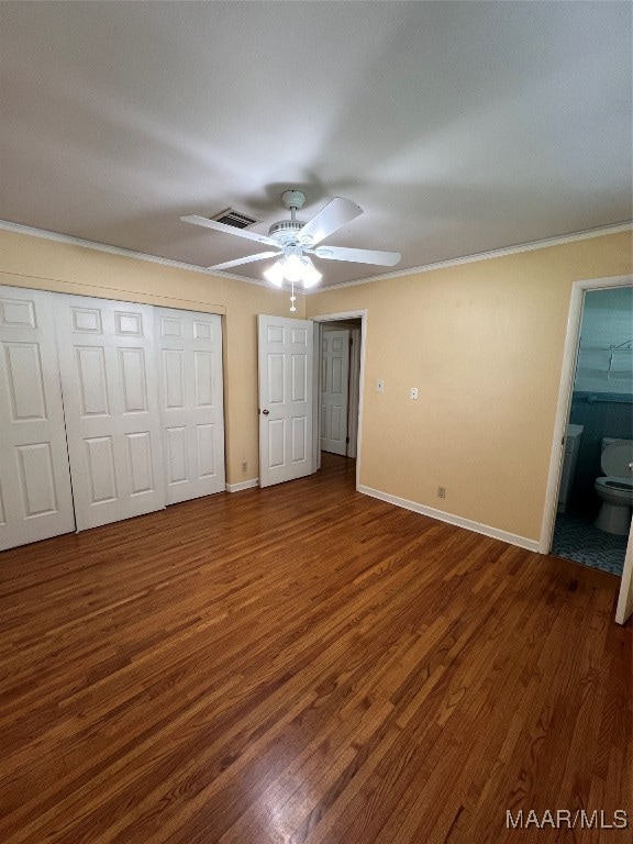 unfurnished bedroom with dark wood-type flooring, ceiling fan, ornamental molding, and ensuite bath