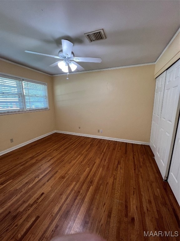 unfurnished bedroom with crown molding, ceiling fan, dark hardwood / wood-style floors, and a closet