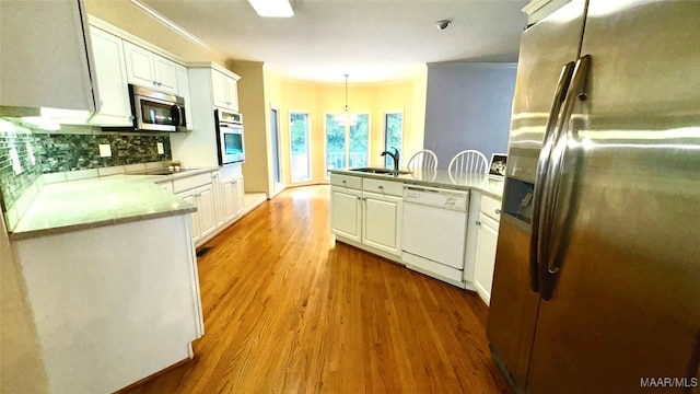 kitchen featuring white cabinets, stainless steel appliances, kitchen peninsula, and sink