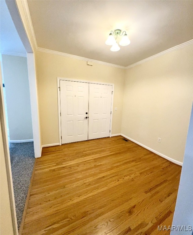 unfurnished bedroom with crown molding, hardwood / wood-style floors, and a closet