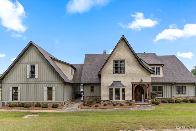 view of front of property with a chimney, roof with shingles, board and batten siding, and a front yard