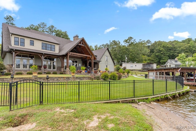 view of front of home featuring a front lawn, a chimney, a water view, and fence