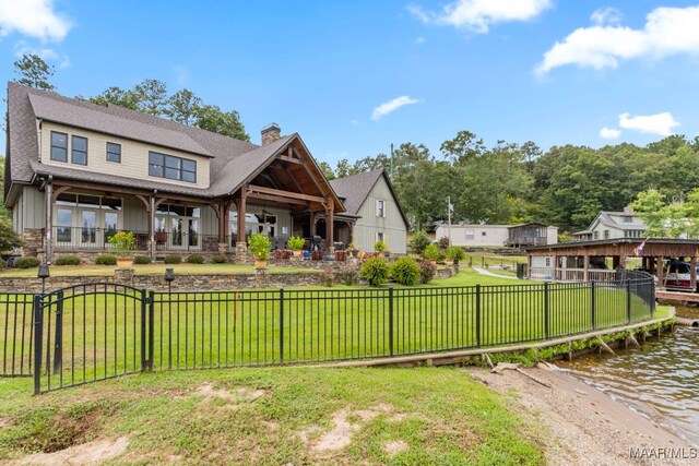 rear view of house with fence private yard, a chimney, a yard, and a water view