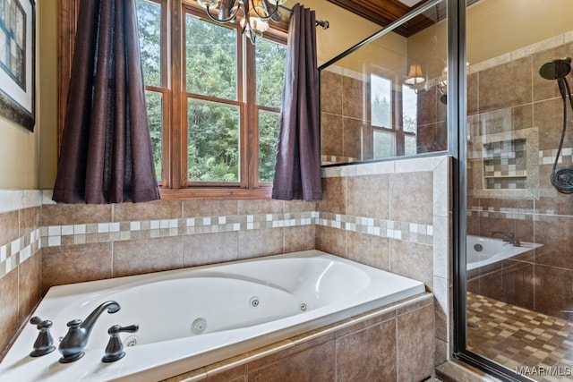 full bathroom with a tub with jets, a stall shower, and a notable chandelier