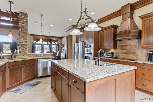 kitchen featuring an island with sink, a sink, custom range hood, appliances with stainless steel finishes, and backsplash