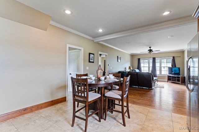 dining area featuring crown molding, light tile patterned flooring, a ceiling fan, and baseboards