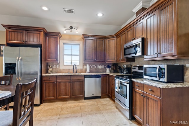 kitchen featuring tasteful backsplash, visible vents, appliances with stainless steel finishes, a sink, and light stone countertops