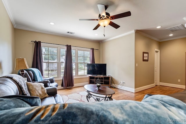 living area with baseboards, wood finished floors, visible vents, and ornamental molding