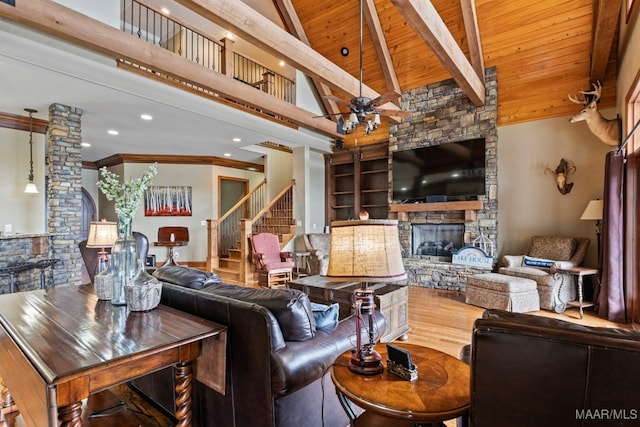 living room with wooden ceiling, ceiling fan, beamed ceiling, wood finished floors, and a stone fireplace