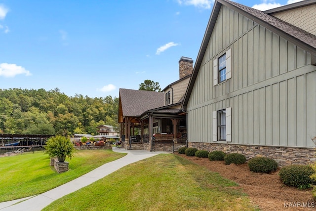 view of side of home with board and batten siding, a yard, and a chimney