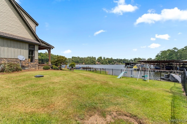 view of yard with a playground, fence, and a water view