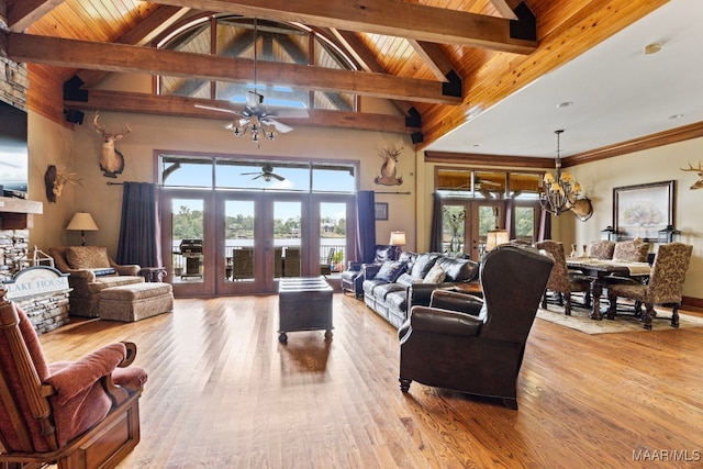 living room featuring light wood finished floors, ceiling fan with notable chandelier, beam ceiling, and french doors