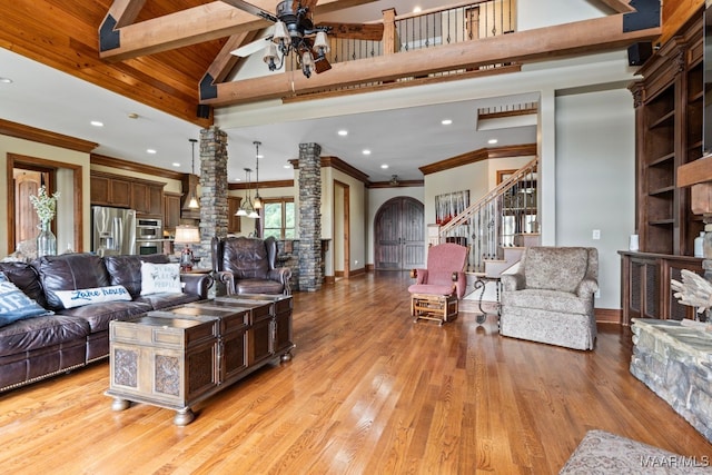 living room with arched walkways, stairway, light wood-style flooring, a ceiling fan, and high vaulted ceiling