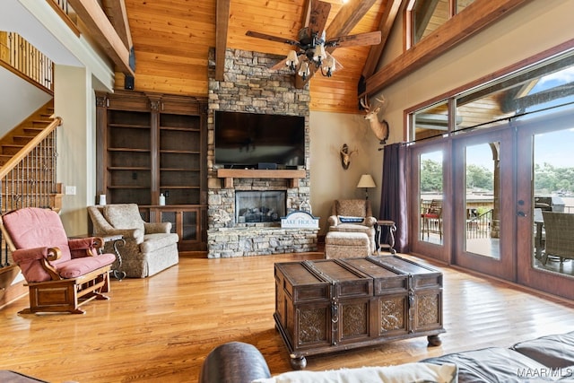 living room with light wood-style flooring, beamed ceiling, and a stone fireplace