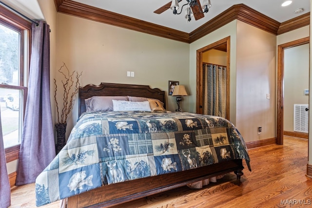 bedroom with crown molding, wood finished floors, visible vents, and baseboards