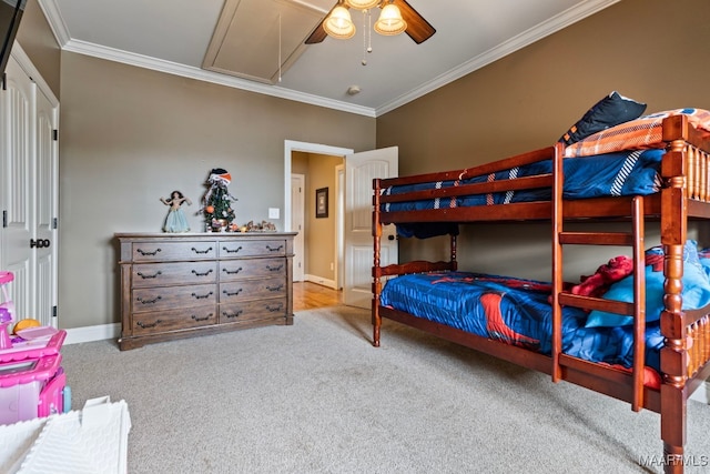 carpeted bedroom with attic access, ornamental molding, ceiling fan, and baseboards