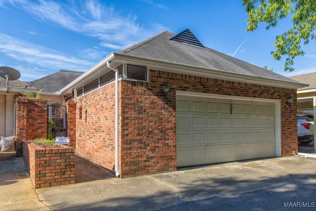 view of side of home with brick siding, an attached garage, and a shingled roof