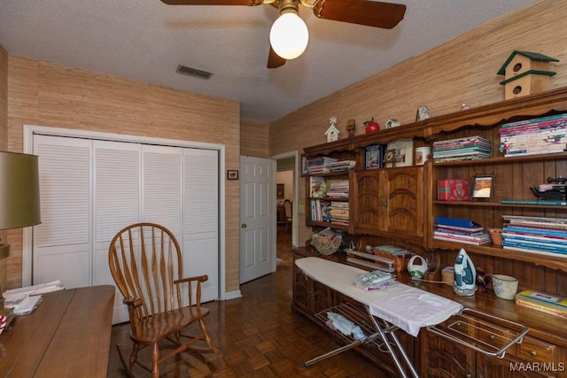 office area with a ceiling fan, visible vents, and a textured ceiling