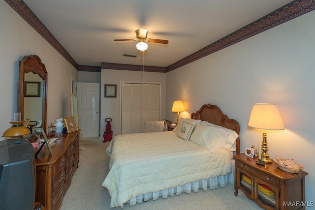 bedroom with light carpet, ornamental molding, ceiling fan, and a closet