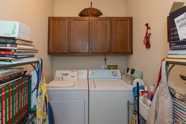 clothes washing area with washing machine and clothes dryer and cabinets