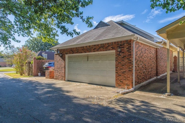 view of home's exterior with brick siding, an attached garage, and roof with shingles