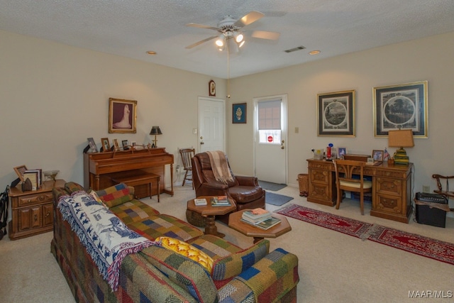 living area featuring a textured ceiling, a ceiling fan, visible vents, and light colored carpet