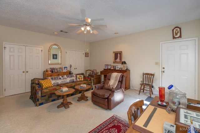 carpeted living area featuring a ceiling fan and a textured ceiling