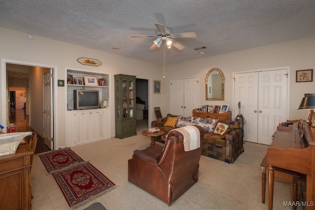 living area with light carpet, a ceiling fan, visible vents, and a textured ceiling