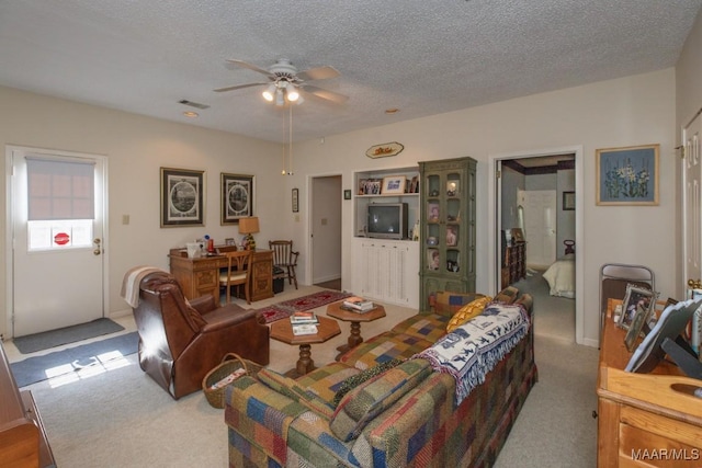 living room featuring a textured ceiling, ceiling fan, carpet floors, and visible vents