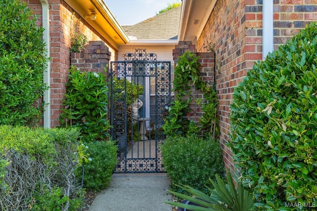 view of exterior entry featuring a gate and brick siding