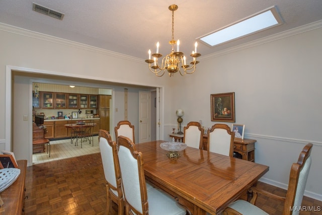 dining room with ornamental molding, visible vents, and an inviting chandelier