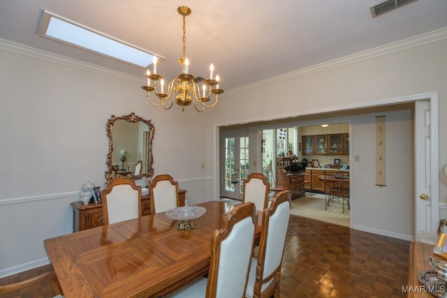 dining space featuring baseboards, an inviting chandelier, visible vents, and crown molding