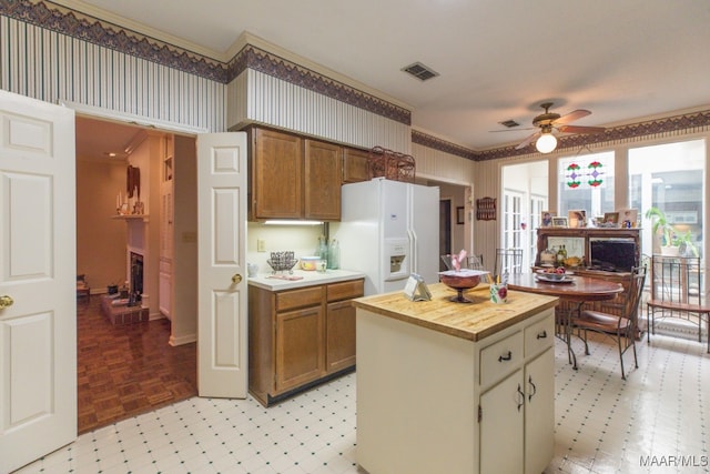 kitchen featuring light floors, white refrigerator with ice dispenser, visible vents, and a fireplace with raised hearth