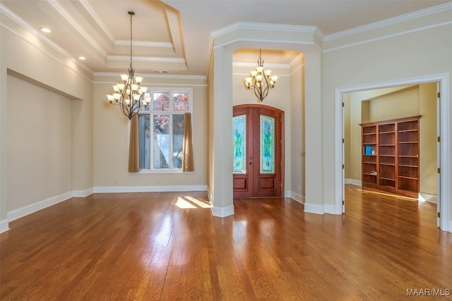 foyer entrance with hardwood / wood-style floors, french doors, ornamental molding, a tray ceiling, and a chandelier