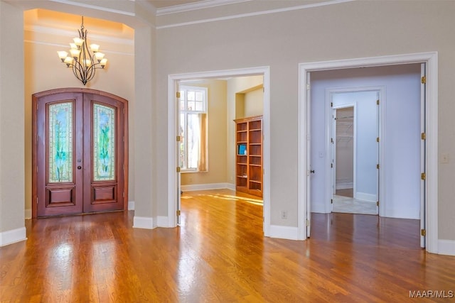 entryway with french doors, hardwood / wood-style flooring, ornamental molding, and a notable chandelier