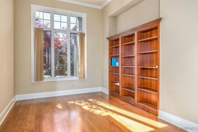 empty room with crown molding, plenty of natural light, and hardwood / wood-style floors